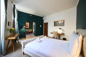 圣艾米隆Les Appartements de la Cadène的卧室配有白色的床和绿色装饰的墙壁