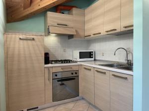 平佐洛瓦伦蒂诺公寓的厨房配有木制橱柜、炉灶和微波炉。