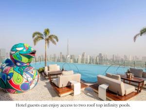 迪拜SLS Dubai Hotel & Residences的一个带椅子和雕像的游泳池的度假酒店