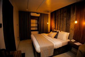 阿沙巴Vic & J Lounge and Hotel Asaba的卧室配有一张带白色床单和枕头的大床。