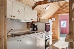 DjurhamnCosy Cottages Close To Water的厨房配有白色橱柜和木制天花板