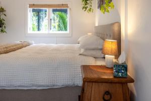 奥克兰Jungle Cottage Escape的卧室配有白色的床和窗户。