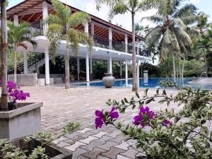 贝鲁沃勒Seetharama Garden of Life的一座带游泳池、棕榈树和紫色鲜花的度假村