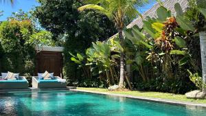 沙努尔Karmagali Suites Adults only & Private Pool Family Villas的一个带两把蓝色椅子和树木的游泳池