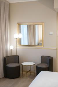 米兰Hotel Nasco的酒店客房带两把椅子和镜子