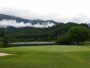 攀牙Katathong Golf Resort & Spa的一座以湖泊和山脉为背景的高尔夫球场