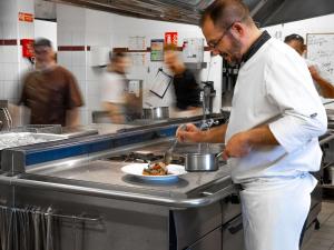 圣米歇尔山圣米歇尔山美居酒店的厨师在厨房准备一盘食物