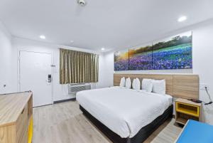 麦金尼麦金尼戴斯酒店的卧室配有一张床,墙上挂有绘画作品