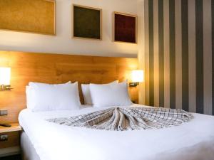 圣拉里苏朗Mercure Saint-Lary的一间卧室配有一张带两盏灯的大型白色床。