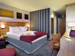 圣拉里苏朗Mercure Saint-Lary的配有一张床和一张书桌的酒店客房