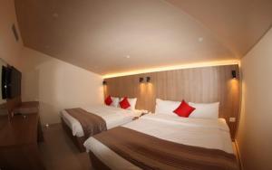 朱尼耶朱尼耶精品酒店的两张位于酒店客房的床铺,配有红色枕头