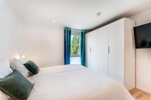 施卢赫湖Luxuswohnung Traumblick - Neubau 2023的卧室配有带绿色枕头的大型白色床