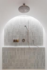 圣于尔萨讷Hôtel de La Cigogne的浴室铺有灰色瓷砖,设有淋浴。