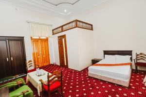 撒马尔罕Yangi Sharq的卧室配有一张床和一张桌子及椅子