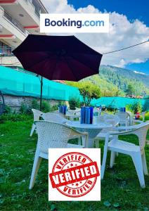 马拉里Hotel Hamta View Manali !! Top Rated & Most Awarded Property in Manali !!的草上带雨伞的白色桌子