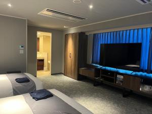 鹿儿岛Sun Days Kagoshima的配有一张床和一台平面电视的酒店客房