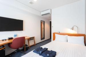 鹿儿岛Sun Days Kagoshima的酒店客房设有一张床、一张书桌和一台电视机。