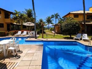 阿拉亚尔达茹达Residence Maria Vittoria Praia Arraial的房屋旁的游泳池配有桌椅