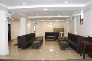 哈里瓦Hotel Prithvi Haridwar - Excellent Stay with Family, Parking Facilities的一间设有黑色皮革沙发和桌子的等候室