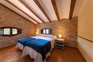 瓦德诺比斯Masia Villa Pilar Valderrobres的卧室配有一张石墙内的大床