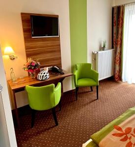 吕德斯海姆老德意志葡萄酒吧高级酒店的酒店客房配有书桌和2把绿色椅子