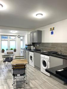 Havering atte BowerPenn Gardens Flat 1 - 2 - 3 & 4 Apartments的厨房配有洗衣机和桌椅