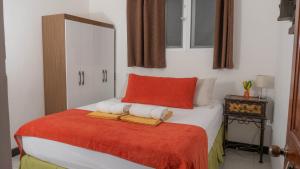 弗洛勒斯AMINA Inn的一间卧室配有一张带红色枕头和毛巾的床