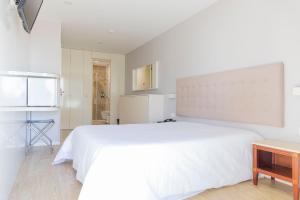 波瓦-迪瓦尔津阿文尼达酒店的白色卧室配有一张大床和一张桌子