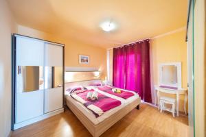 拉布Guesthouse Mira的一间卧室配有一张带粉红色窗帘的大床
