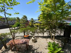 高山Guesthouse Takayama Hanzansha的公园长凳,坐在有树的院子中
