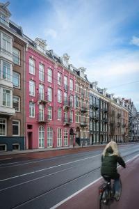 阿姆斯特丹Krisotel的骑着自行车在街道上与建筑物在一起的女人