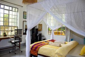 KikimaThe Mbooni Guest House的卧室配有一张床、一张书桌和窗户。