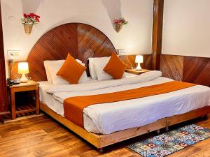 马拉里Ganga Cottage !! 1,2,3 bedrooms cottage available near mall road manali的一间卧室配有一张带橙色和白色枕头的大床