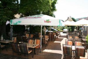 Oberstenfeld欧莱可酒店的室外餐厅,配有桌椅,位于伞下