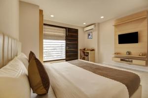 古尔冈Limewood Stay - Corporate Huda City Centre的一间卧室配有一张大床和电视