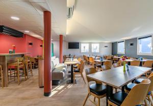 科尔马B&B HOTEL Colmar Lumière的餐厅设有木桌和椅子,拥有红色的墙壁