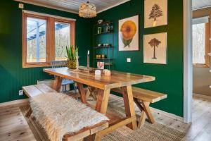 LjungbyhedCosy cabin w fireplace 3 mins from Söderåsen Park的一间设有木桌和绿色墙壁的用餐室