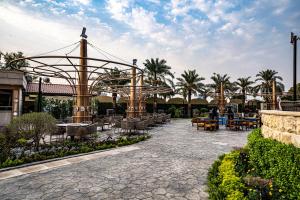 巴格达Babylon Rotana Hotel的庭院配有桌椅和棕榈树