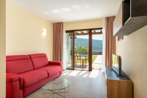加尔尼亚诺Residence Dany appartamenti con cucina vista lago piscina e parcheggio的客厅配有红色的沙发和玻璃桌