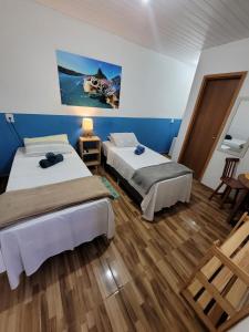 费尔南多 - 迪诺罗尼亚Batera House Noronha的配有蓝色墙壁和木地板的客房中的两张床