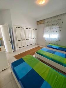 NaktaDar Douja à Chaffar / Ton chez-toi près de la plage的一间配备有两张床及白色和蓝色的卧室