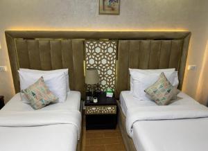 开罗Royal Golden Pyramids Inn的配有白色枕头的酒店客房内的两张床