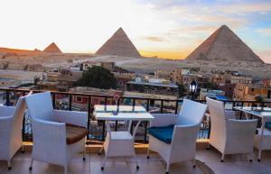 开罗Royal Golden Pyramids Inn的一个带金字塔的后阳台的桌椅