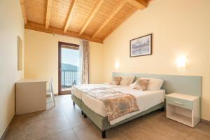 加尔尼亚诺Residence Dany appartamenti con cucina vista lago piscina e parcheggio的一间卧室设有一张床和一个大窗户