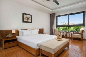 岘港Ocean Beach Resort Da Nang的一间卧室配有一张床、一张桌子和一个窗户。