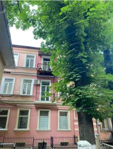 敖德萨Елисаветинская 15的前面有棵树的粉红色建筑