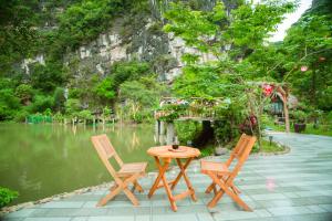 宁平Hoang Minh Mountainside Villa的湖畔的一张桌子和两把椅子