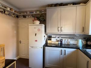 温莎Private Apartment in Windsor的厨房配有白色橱柜和白色冰箱。