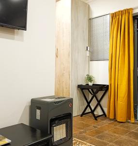 哈里史密斯Olive Tree Studio Apartment的一间设有加热器、桌子和黄色窗帘的房间