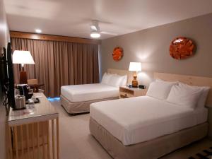 El RobleFiesta Resort All Inclusive Central Pacific - Costa Rica的酒店客房设有两张床和电视。